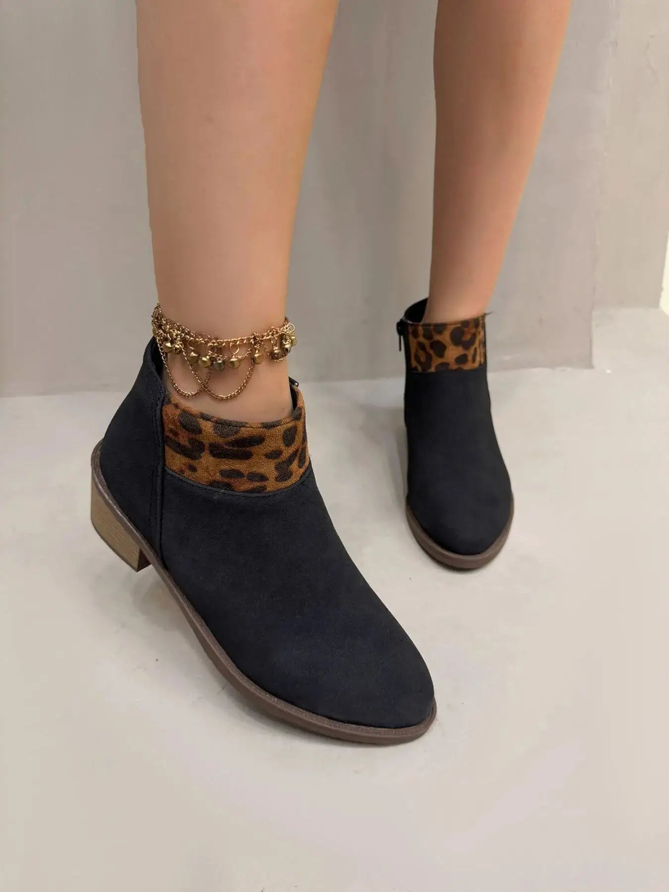 Black ankle boots with leopard print trim and a gold anklet.