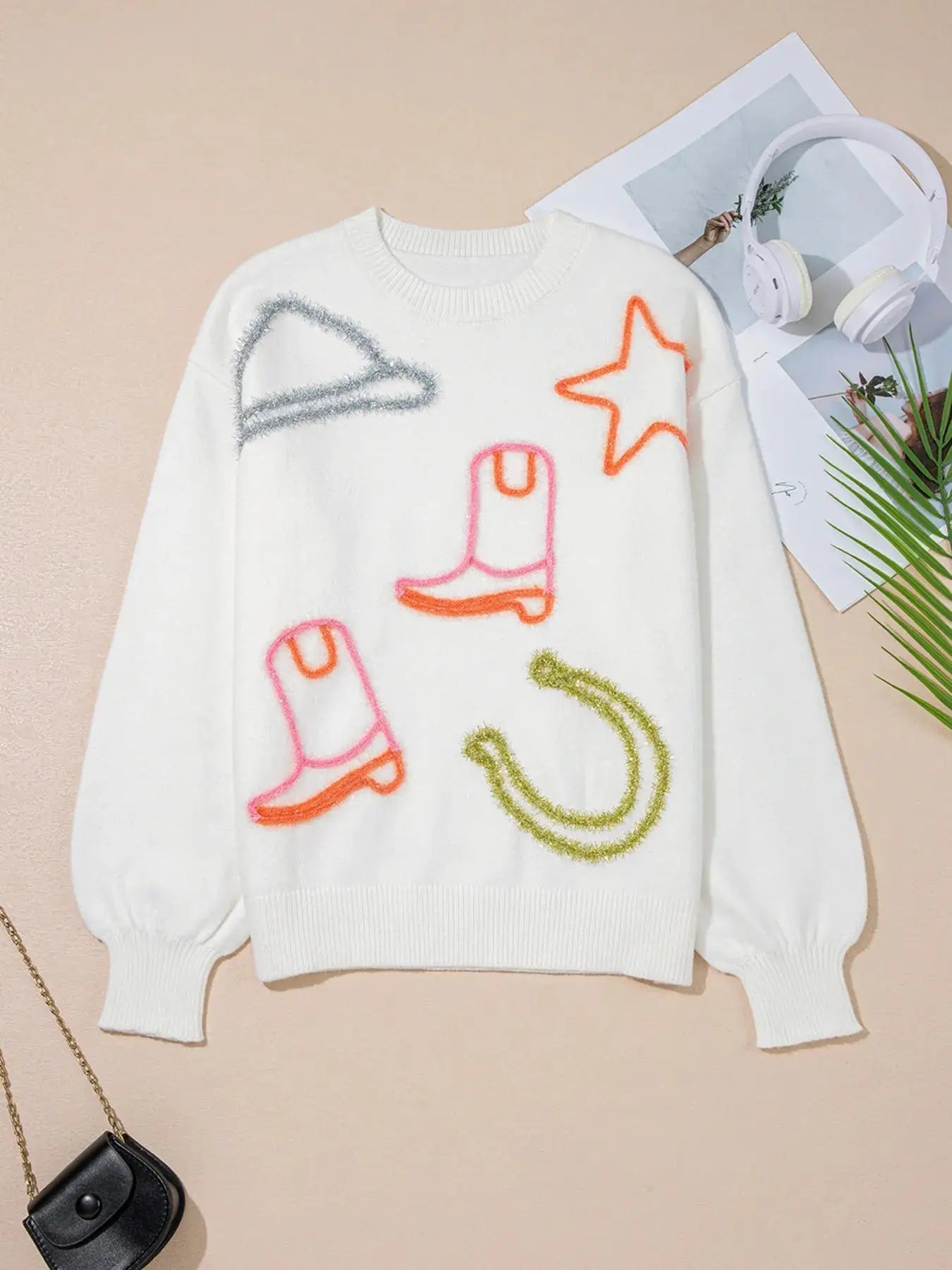 White knit sweater with western-themed embroidered designs.