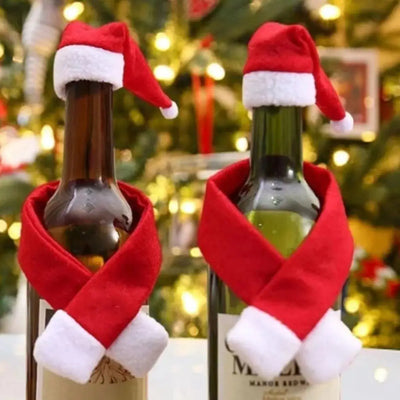 Two wine bottles are decorated with red Santa hats and scarves.