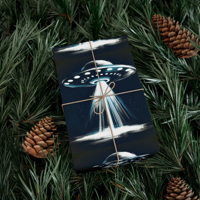 Wrapping paper with a dark blue background featuring a UFO with a beam of light, surrounded by pine needles and pinecones.