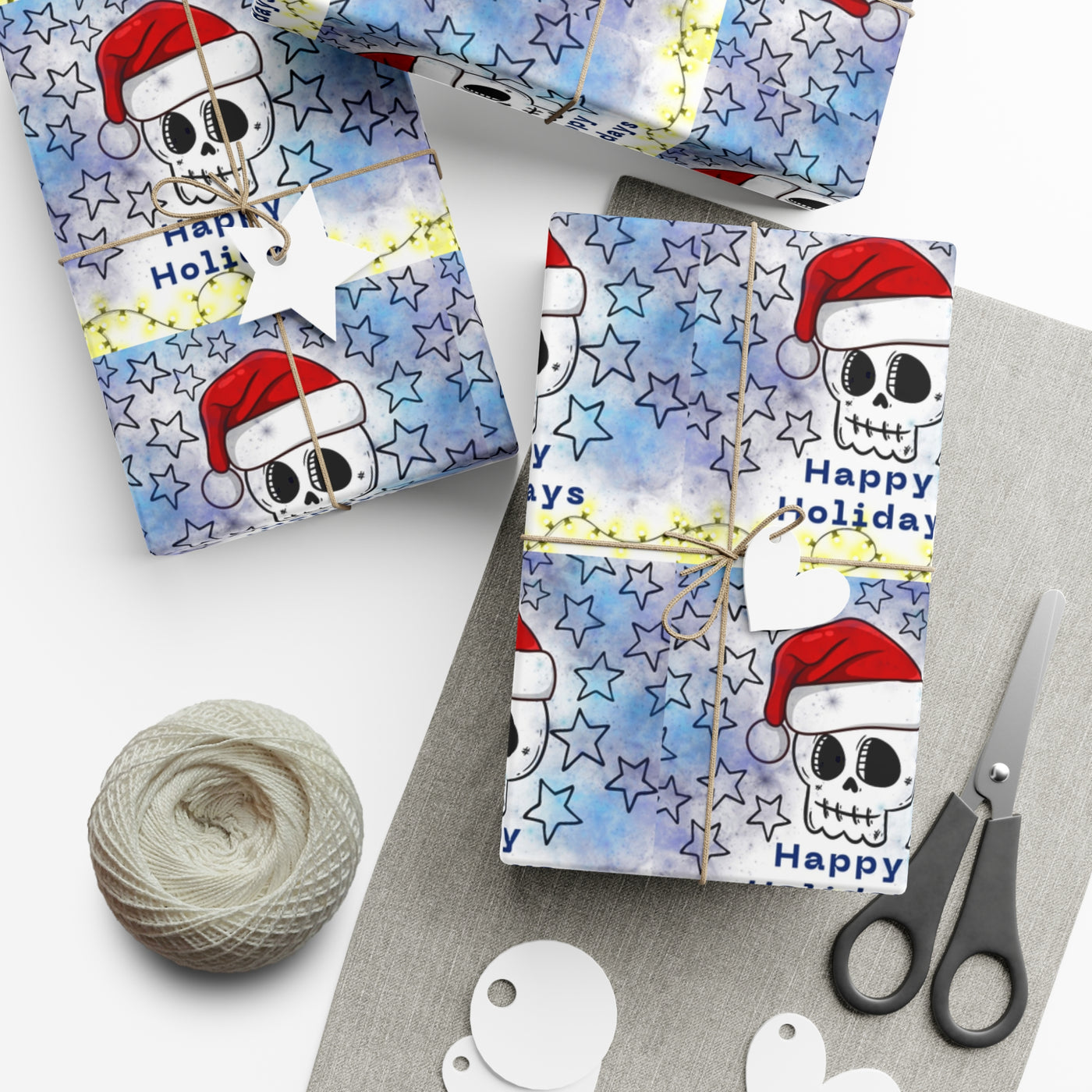 Gift wrap with a blue watercolor background, black stars, and skulls wearing Santa hats.