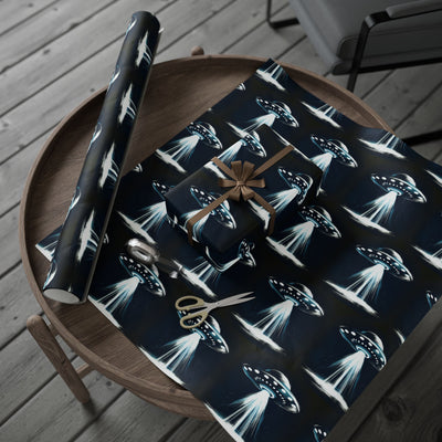 UFO-themed wrapping paper on a wooden table with scissors and a gift.