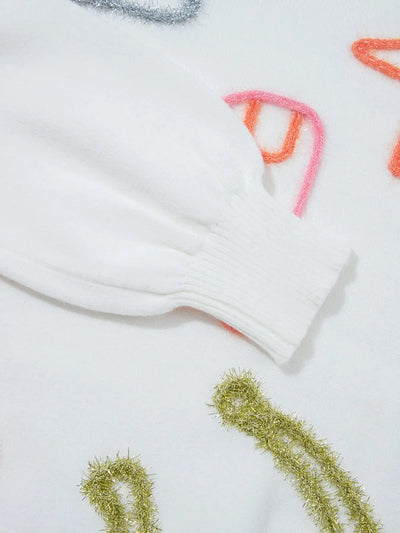 White knit sweater sleeve with colorful fuzzy embellishments.