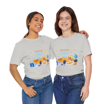 Two women in light grey t-shirts with a Hanukkah graphic print stand with arms around each other.