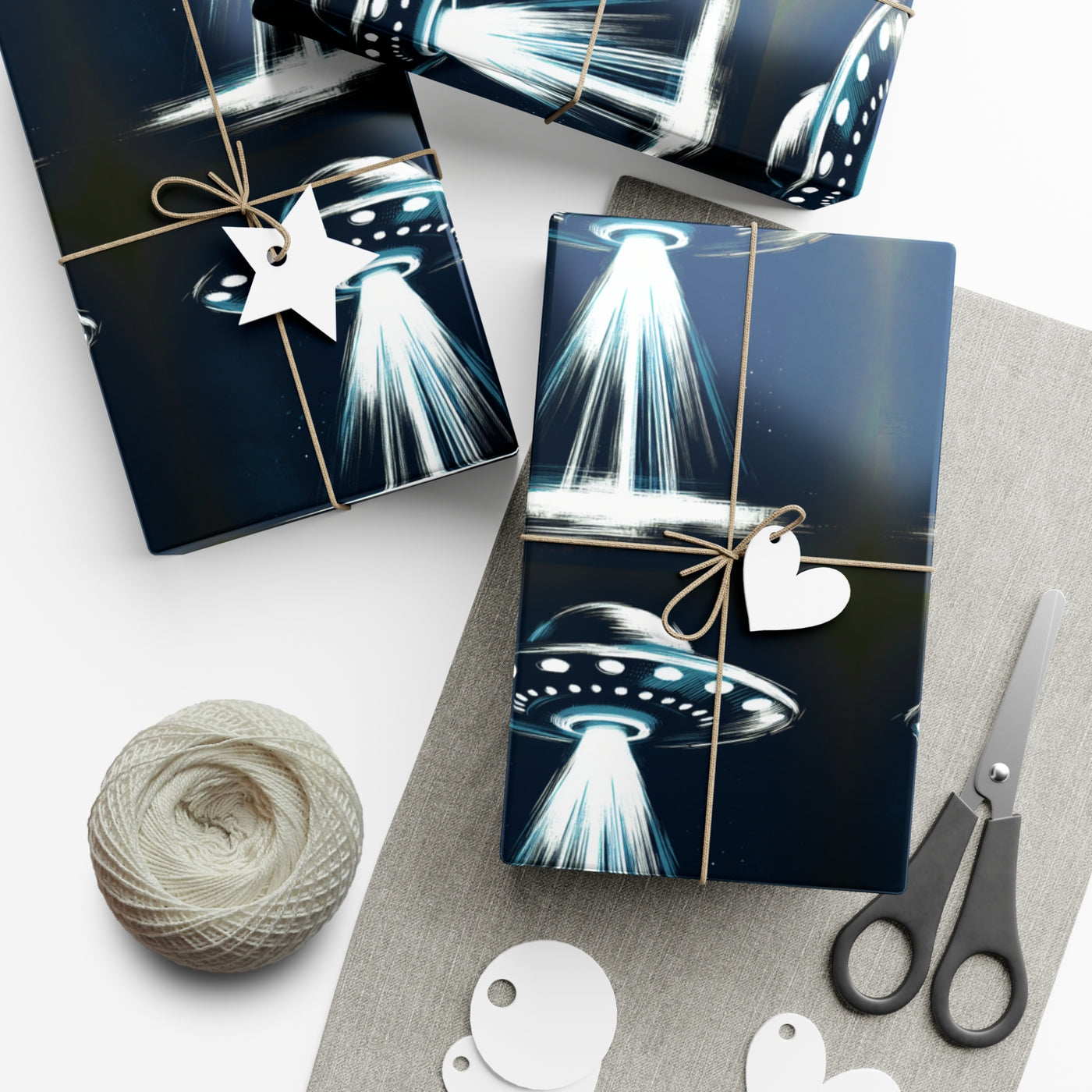 Wrapping paper with a dark blue background featuring a repeating pattern of white and blue UFOs with beams of light.