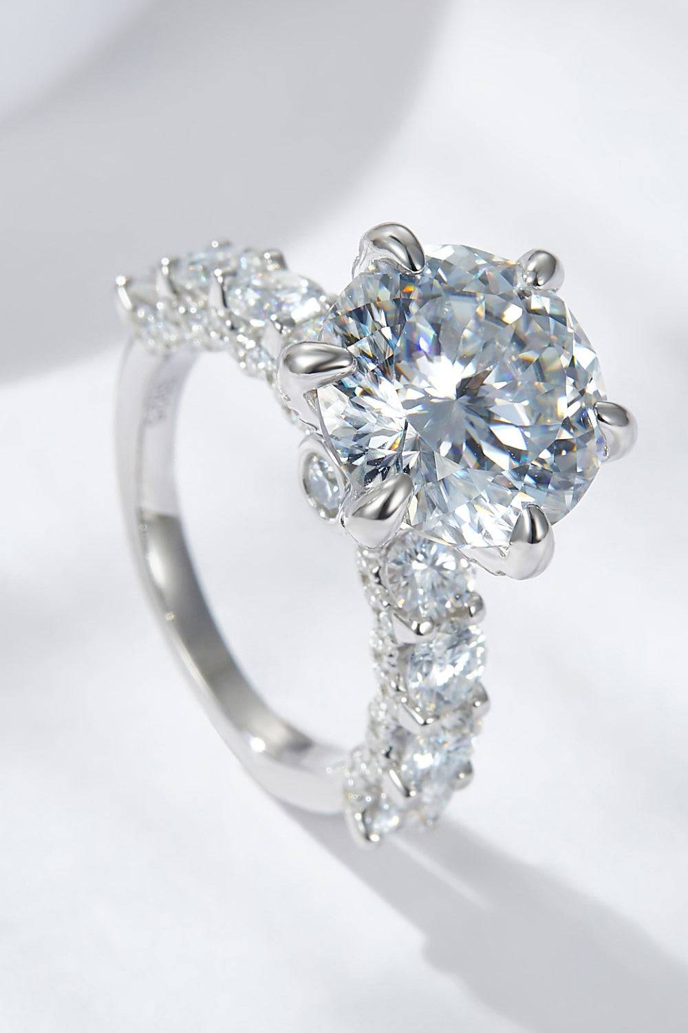 A platinum-plated sterling silver ring with a large central moissanite and smaller stones on the band.