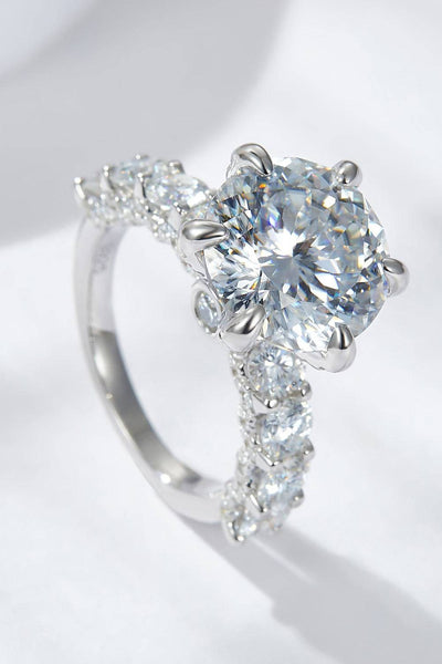 A platinum-plated sterling silver ring with a large central moissanite and smaller stones on the band.