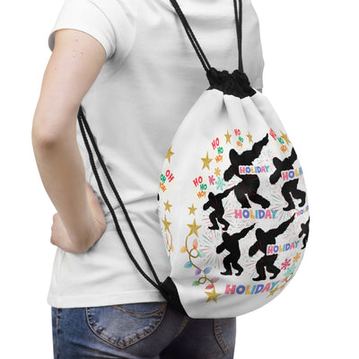 White drawstring bag with a repeating pattern of black Sasquatch silhouettes and holiday text.