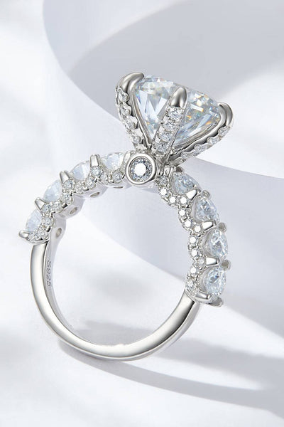 A platinum-plated sterling silver ring with a large central moissanite and smaller accent stones.