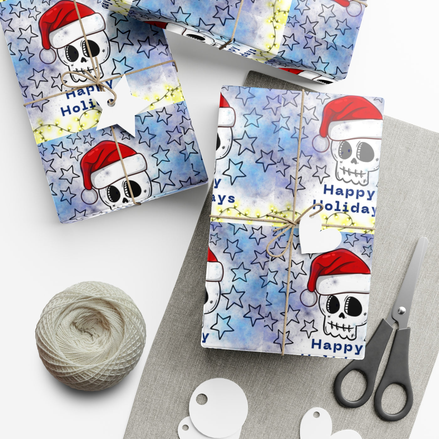 Gift wrap with a blue watercolor background, black stars, and skulls wearing Santa hats.