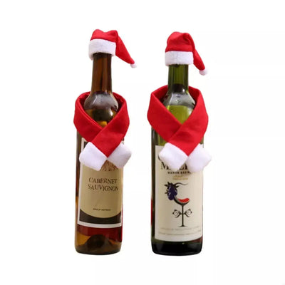 Two wine bottles are decorated with Santa hats and red scarves.