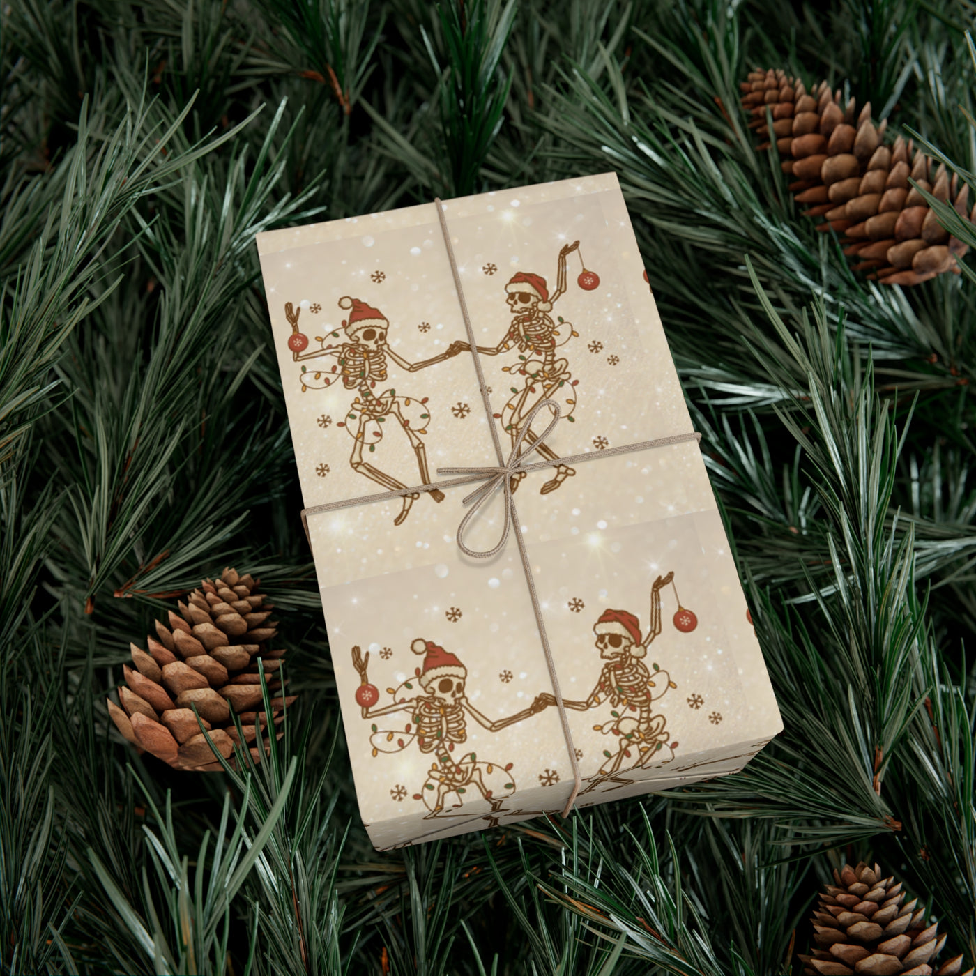 Gift wrap with a skeleton design on a light background, surrounded by pine needles and pinecones.