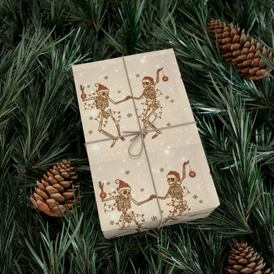 Gift wrap with a skeleton design on a light background, surrounded by pine needles and pinecones.