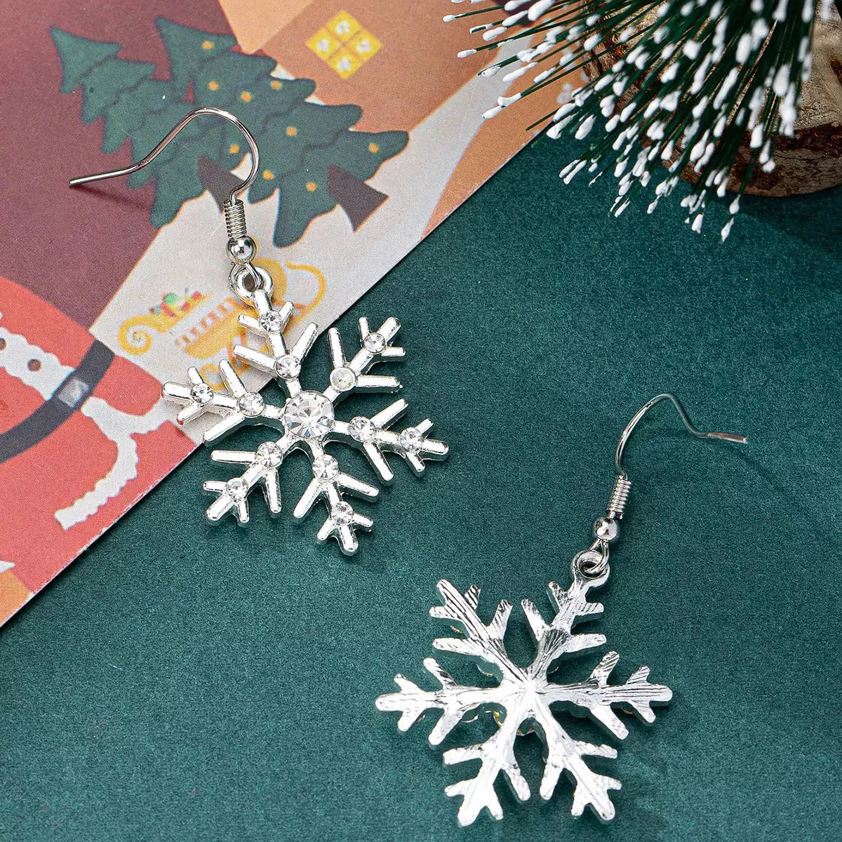 Silver-plated rhinestone snowflake dangle earrings.