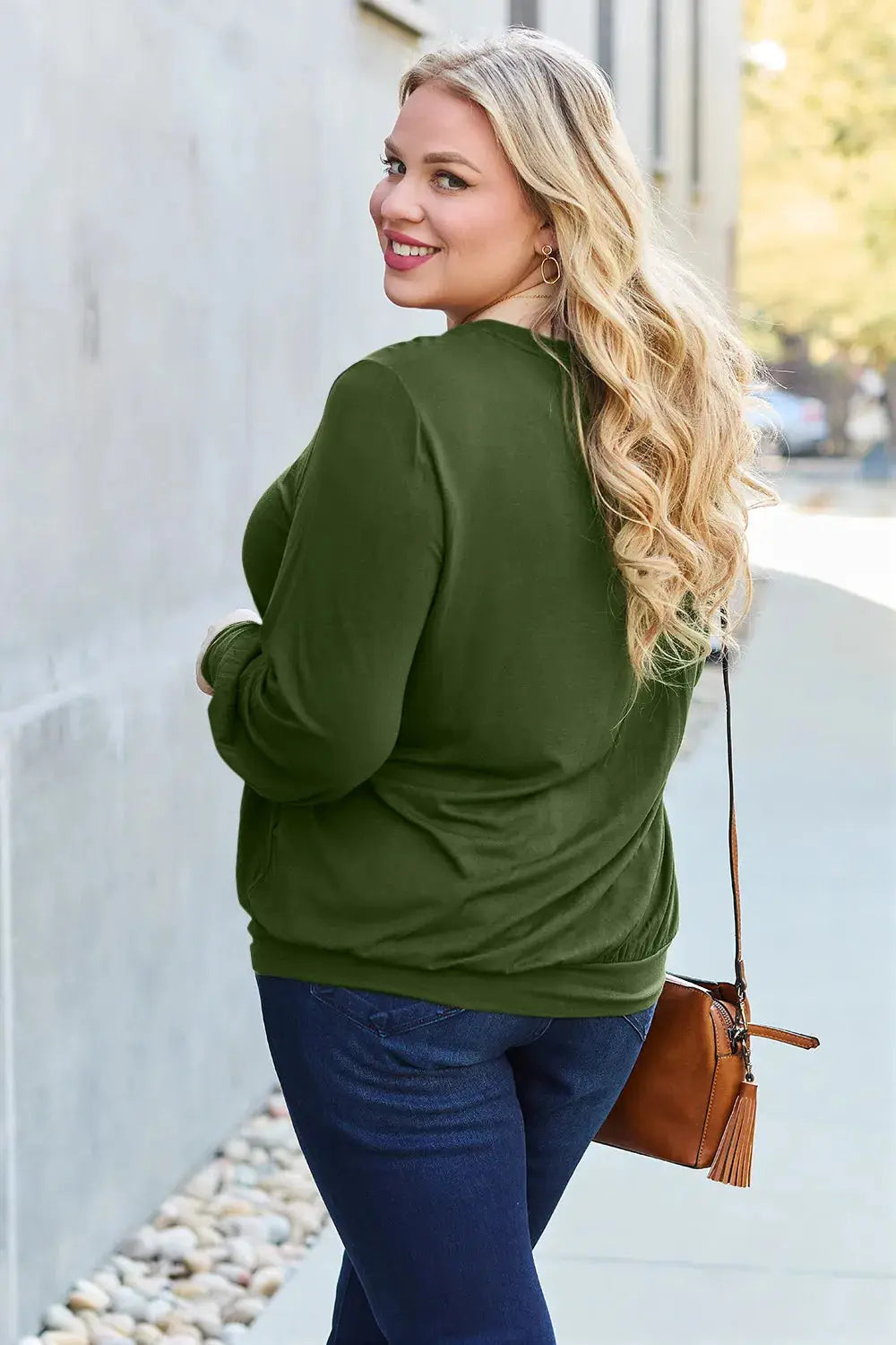 Woman in a green v-neck top and blue jeans.
