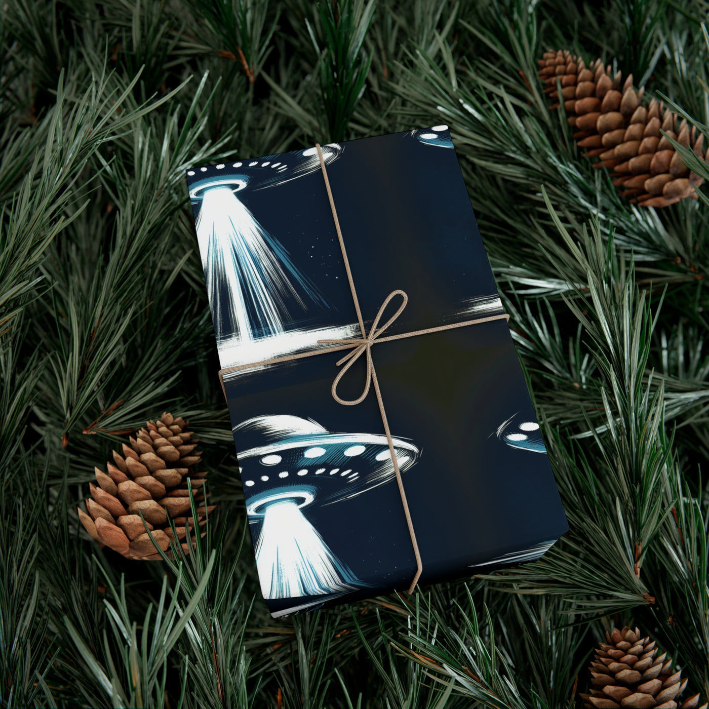 Wrapping paper with a dark blue background featuring a repeating pattern of white and blue UFOs with beams of light, tied with twine.
