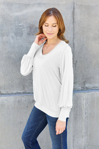 White v-neck top with lantern sleeves and a cinched hem.