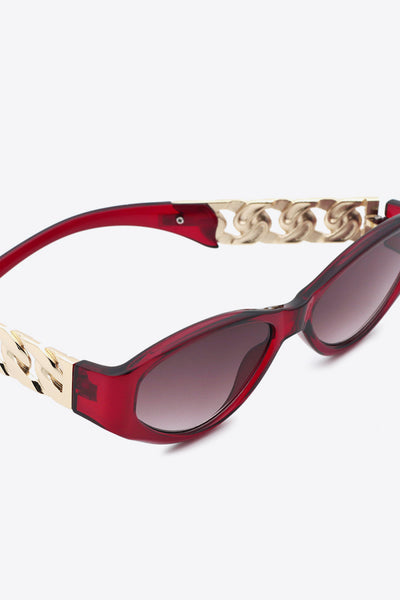 Red cat-eye sunglasses with gold chain detail on the temples.