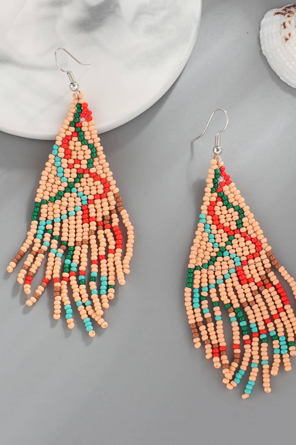 Beaded earrings with a triangular design in peach, red, green, and blue.