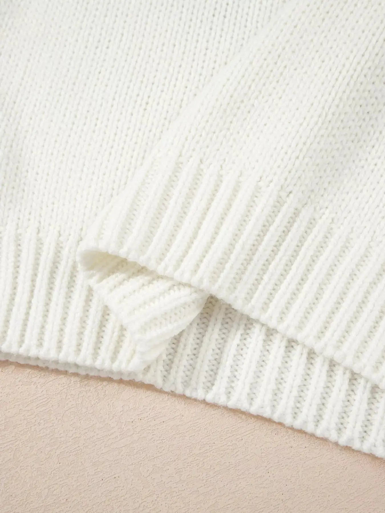 A white knit sweater with ribbed cuffs and hem.