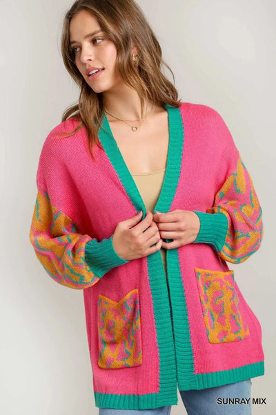 Pink open-front cardigan with green trim and animal print sleeves and pockets.
