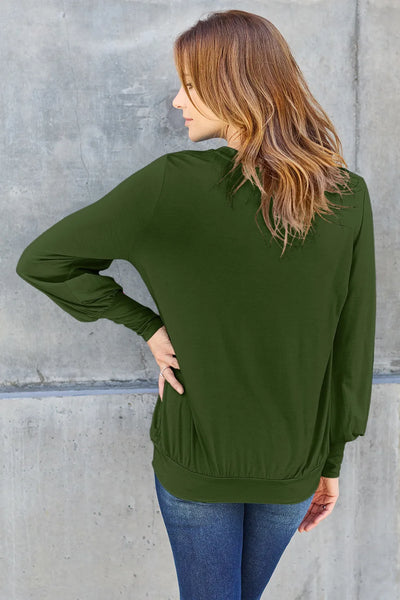 Woman in a green V-neck long-sleeve top with lantern sleeves.