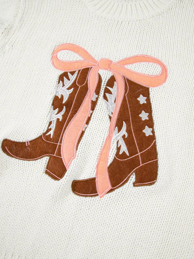 White knit sweater with embroidered cowboy boots and pink bow detail.
