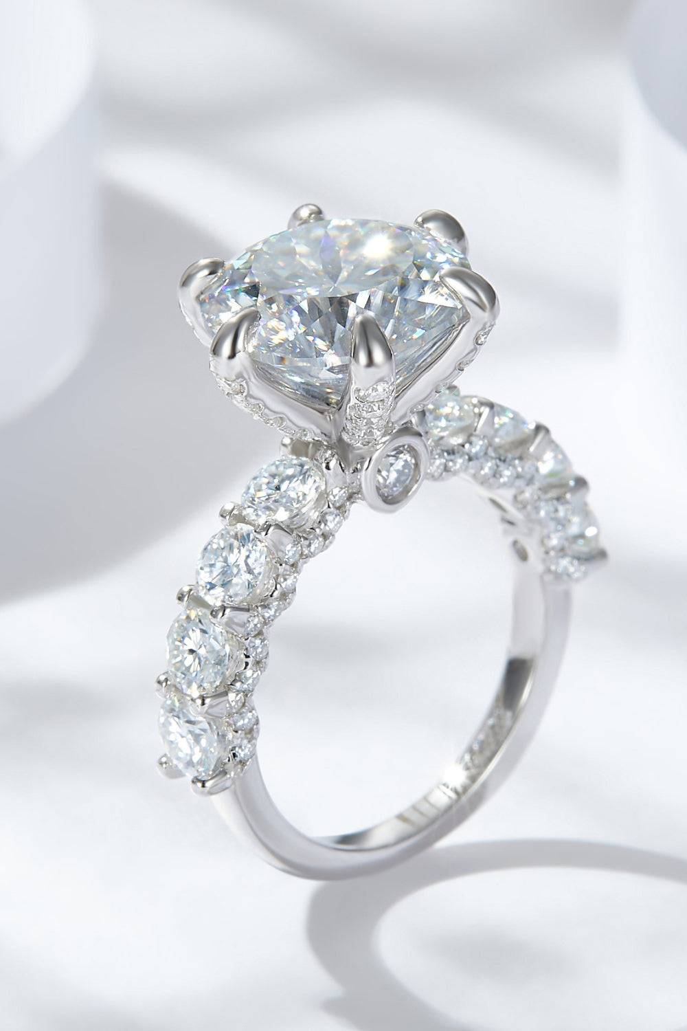 A platinum-plated sterling silver ring with a large central moissanite and smaller stones.