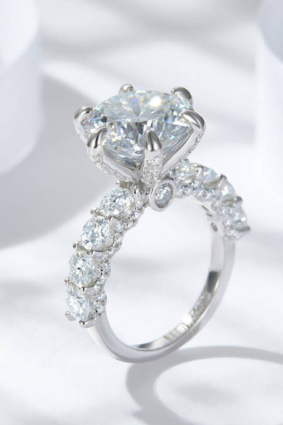 A platinum-plated sterling silver ring with a large central moissanite and smaller stones.