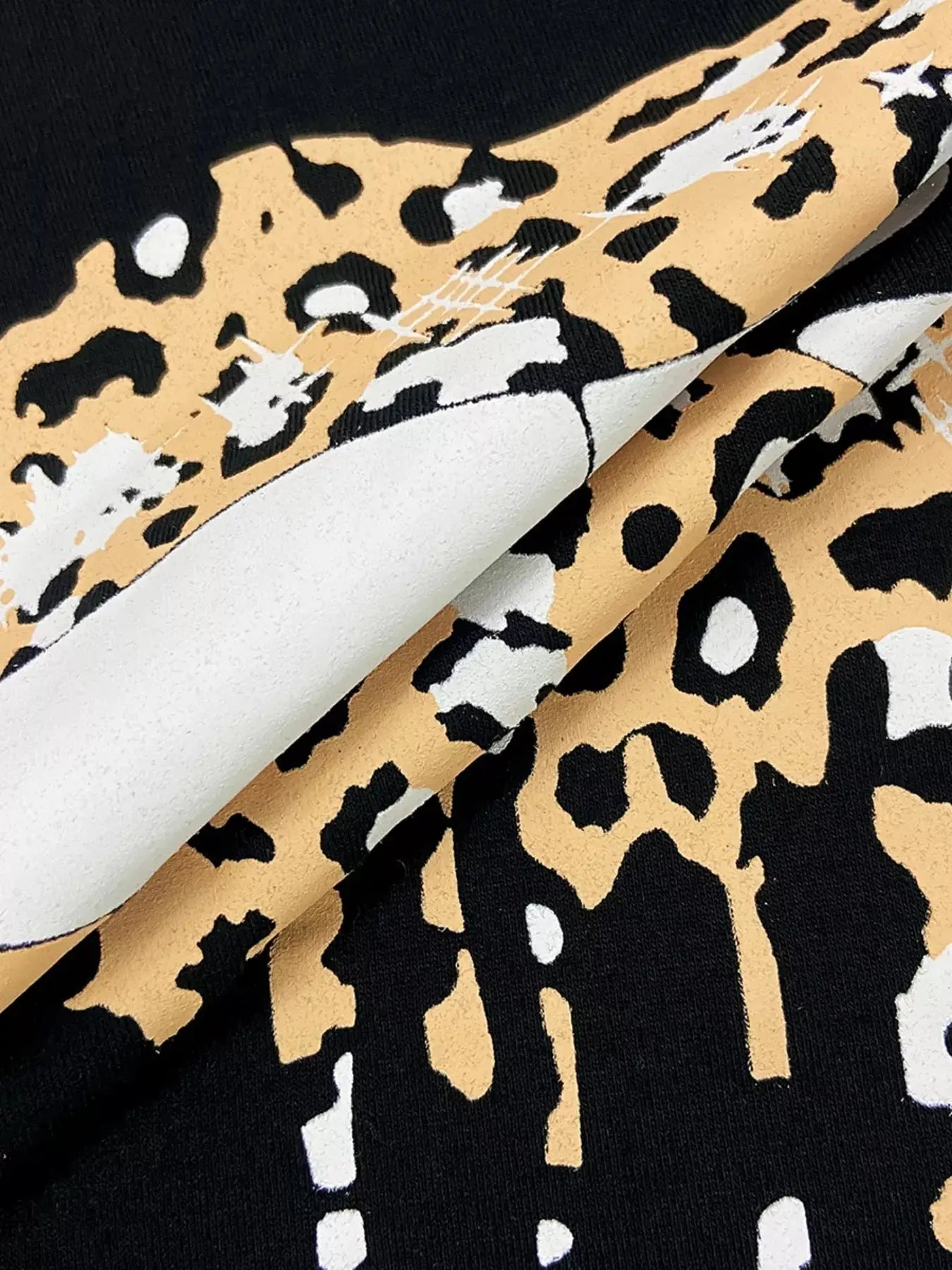 Black t-shirt with a tan and white abstract leopard print design.