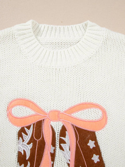 White knit sweater with embroidered cowboy boots and a pink bow.