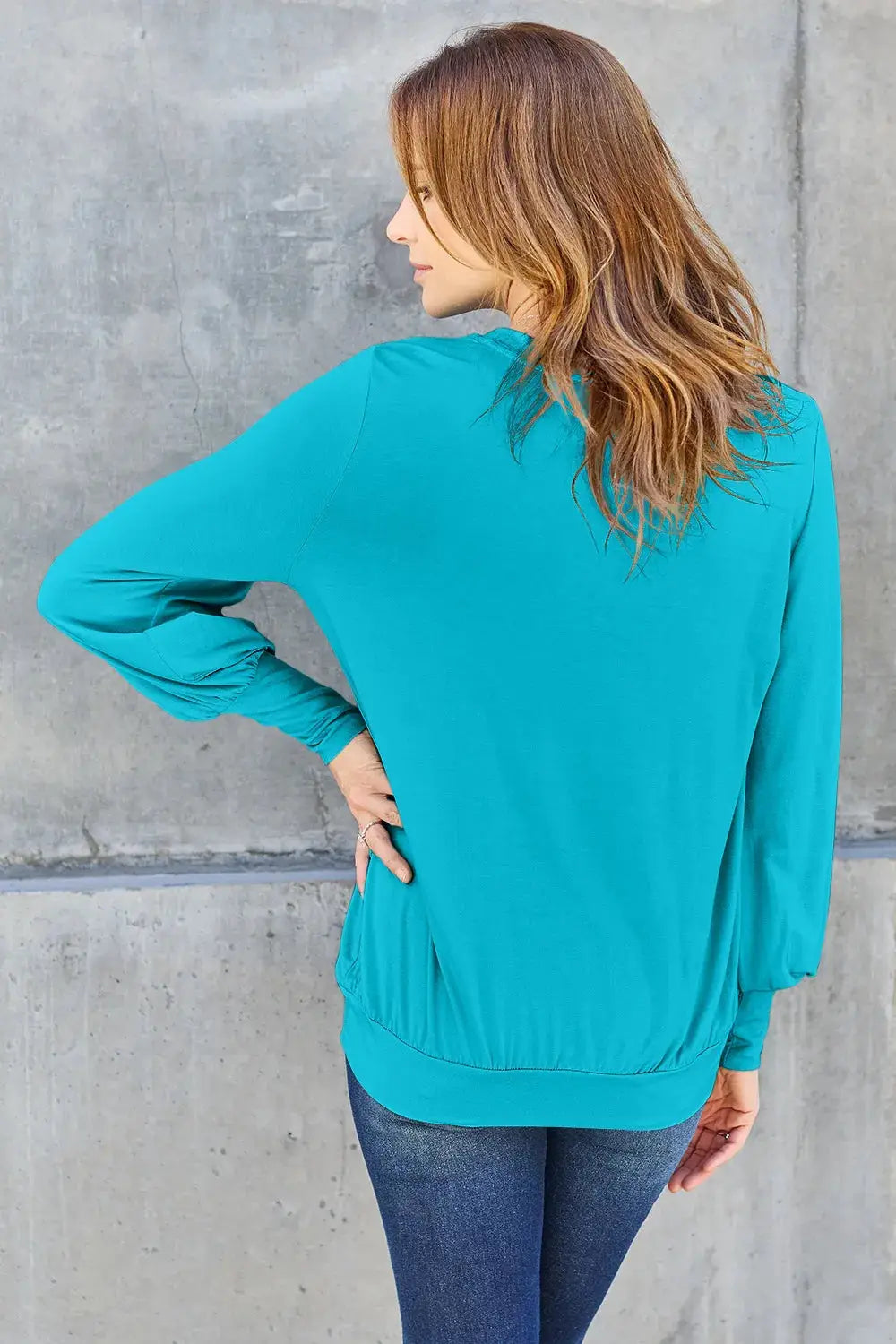 Turquoise v-neck top with lantern sleeves and a cinched hem.