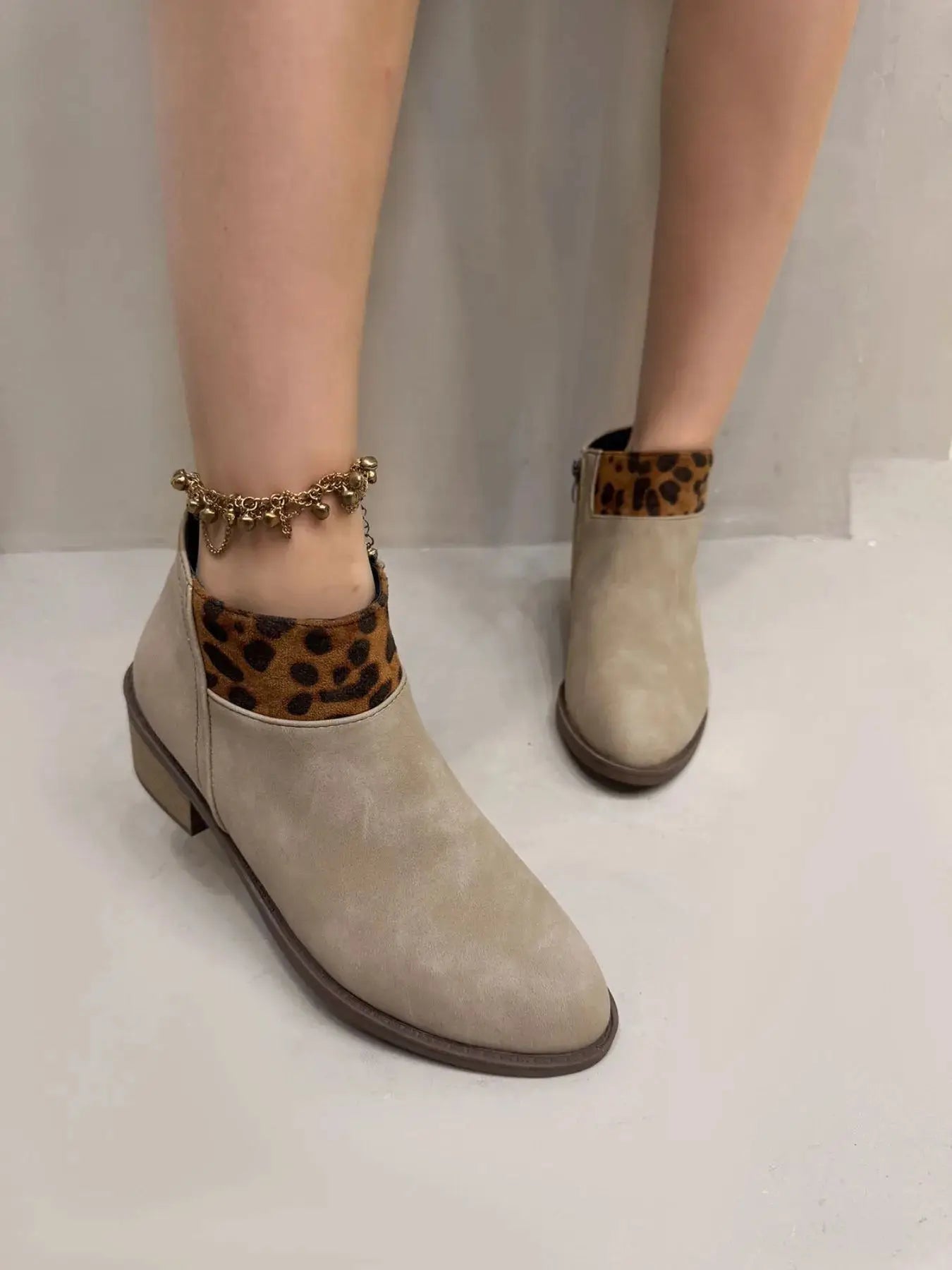 Beige suede ankle boots with leopard print trim and a gold anklet.