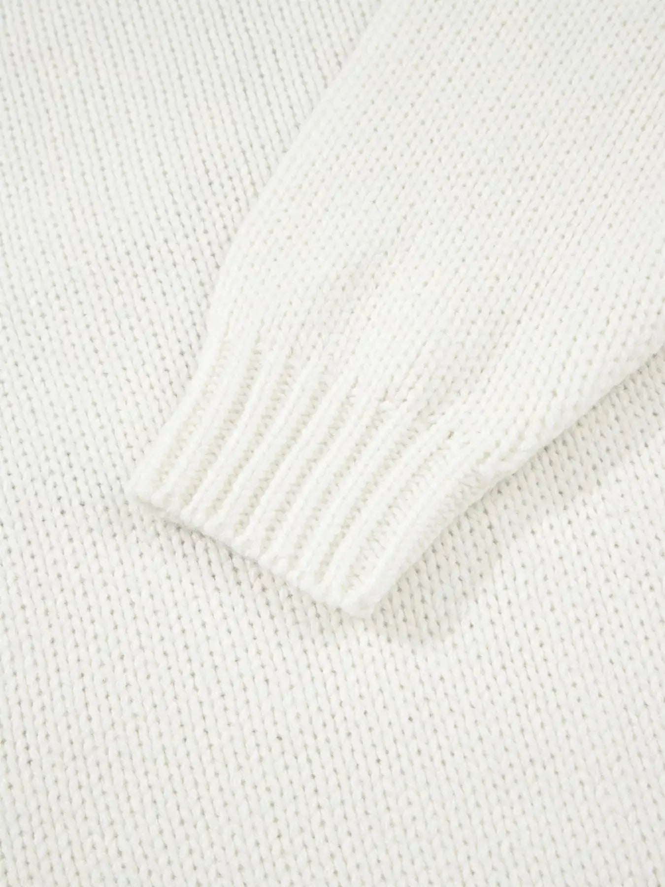 A white knit sweater with a ribbed cuff.