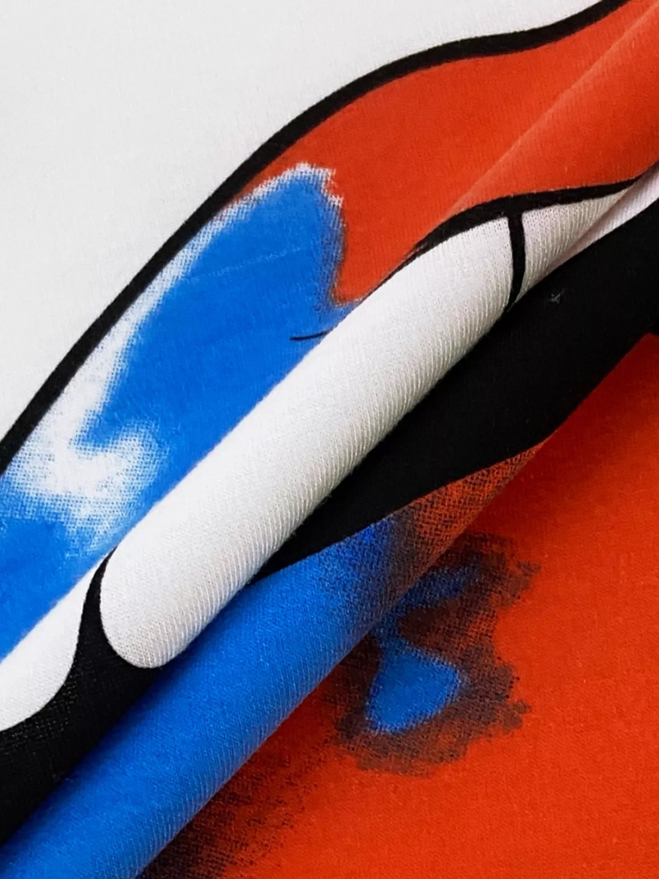 Graphic t-shirt with abstract red, blue, and black design on white fabric.