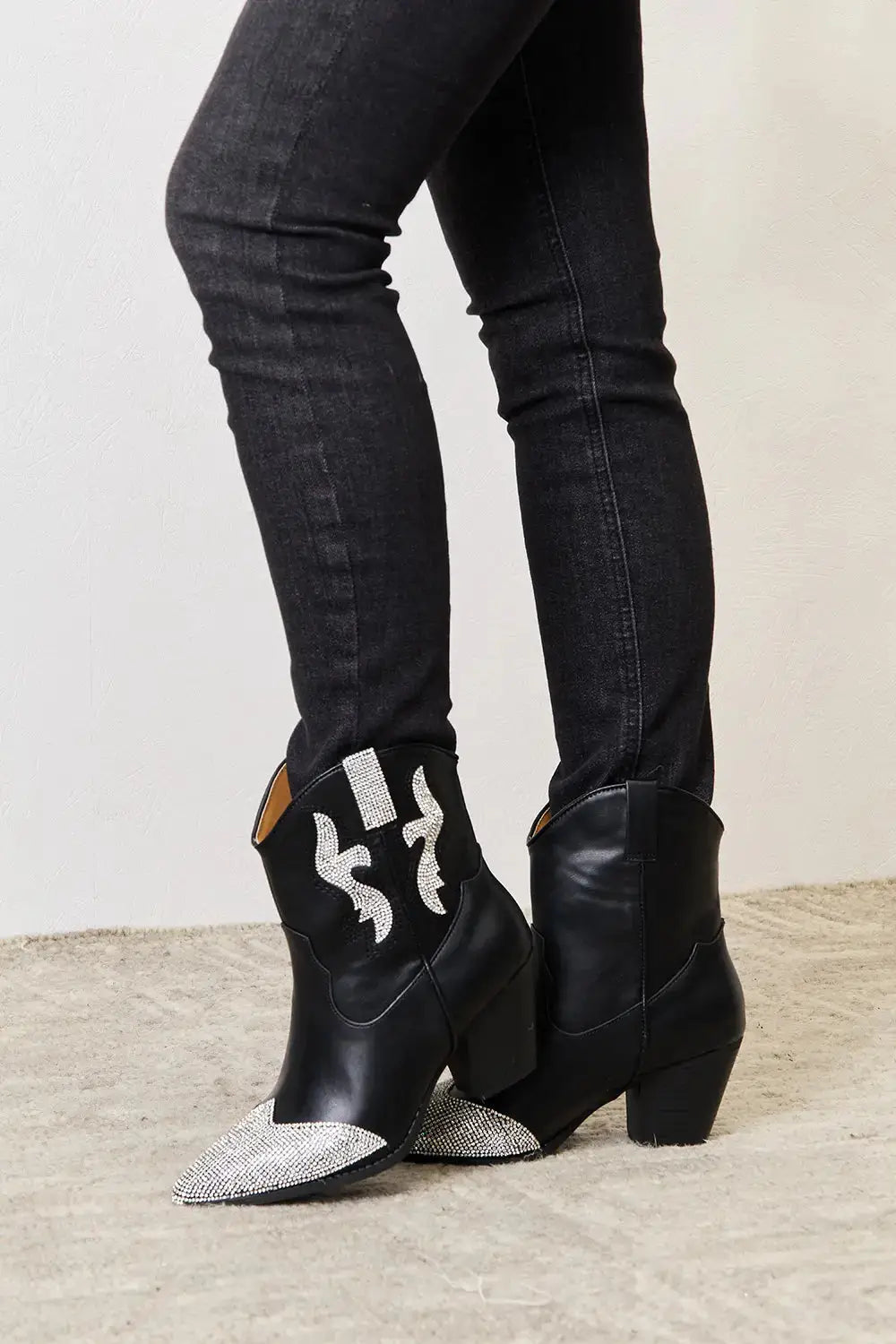Black ankle boots with rhinestone accents and a pointed toe.